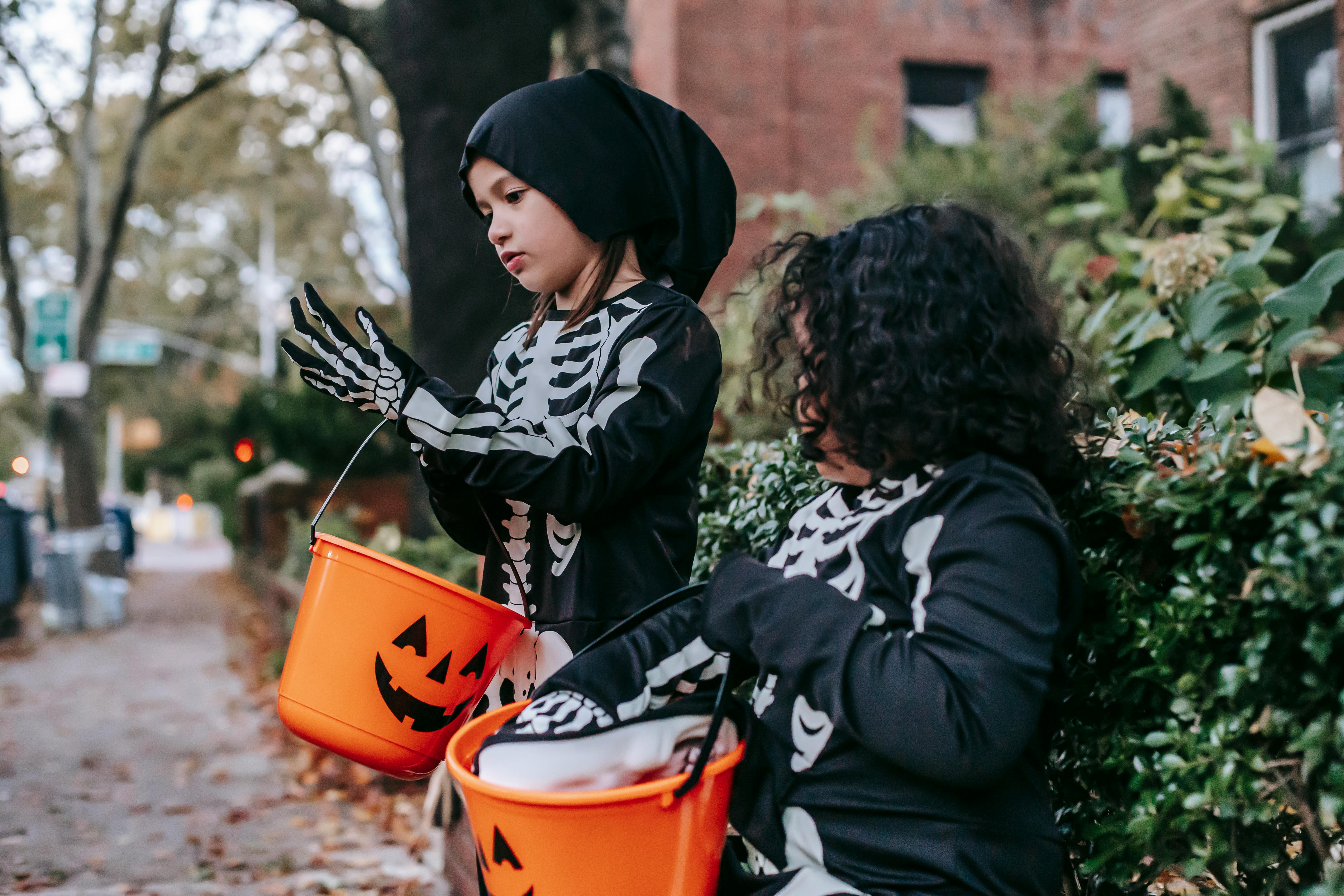 Children carrying pumpkin buckets while trick-or-treating for Halloween boo basket inspiration